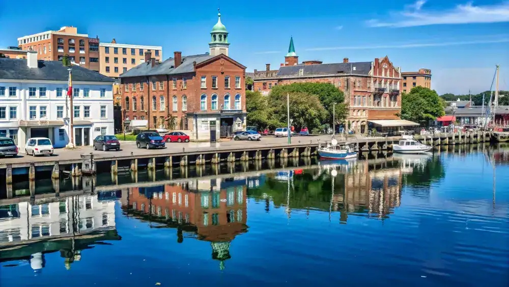 New Brunswick's historic waterfront, reflected in calm water along the pier, representing In Good Nutrition's commitment to empowering New Brunswickers with personalized dietitian support.