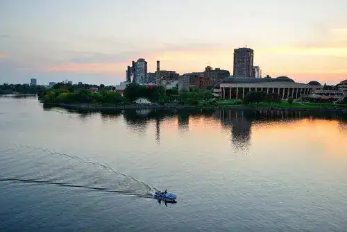 Kitchener-Waterloo's sunset river with a boat drifting past reflected buildings, representing In Good Nutrition's commitment to empowering Kitchener-Waterloo residents with personalized dietitian support.