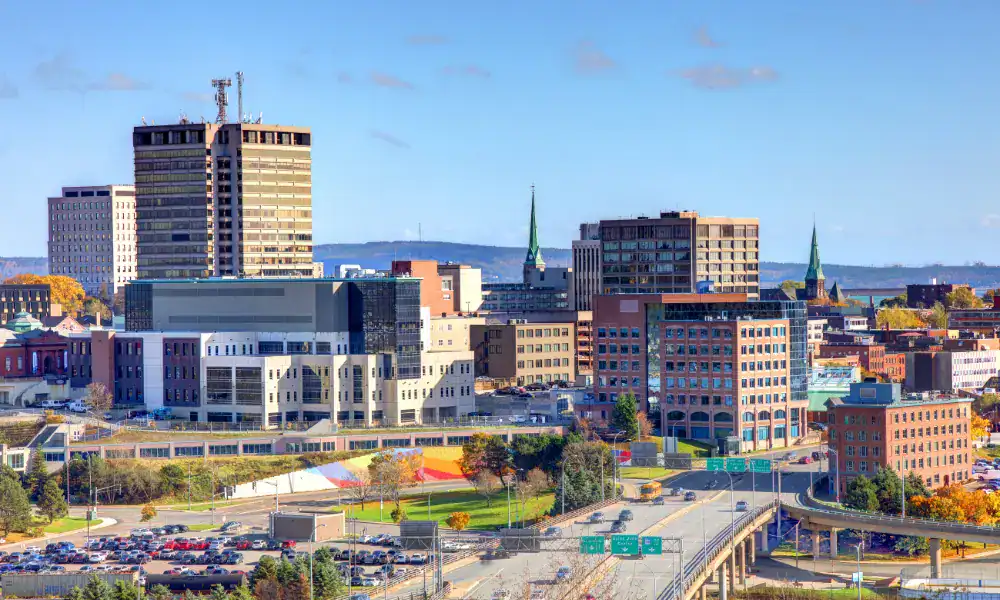 Saint John's downtown skyline with steeples and fall colour against a clear sky, representing In Good Nutrition's commitment to empowering Saint John residents with personalized dietitian support.